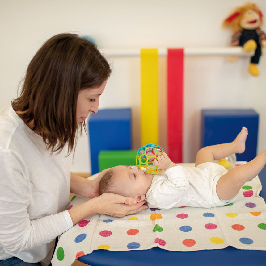 TherapeutIn macht eine Übung mit Säugling